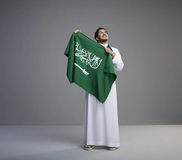 Smiling Saudi Man Holding National Flag in Studio