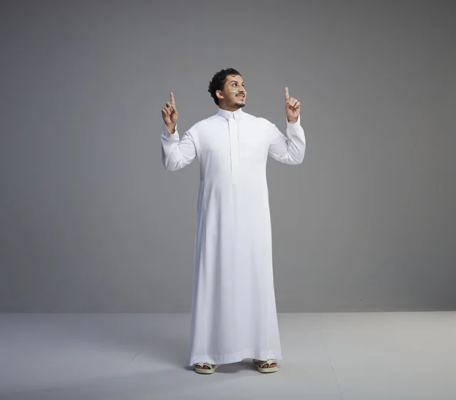 Saudi Man Pointing Up with Face Paint on Grey Background