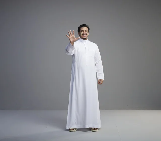 شاب سعودي بالثوب التقليدي يحتفل برسم على الوجه في استوديو