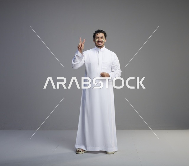 شاب سعودي بالثوب الأبيض يحتفل بعلامة النصر