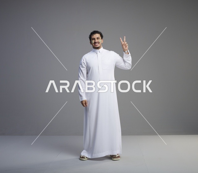 شاب سعودي بالثوب الأبيض يرفع علامة النصر