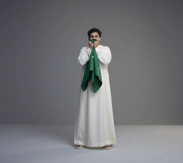 Saudi Man Kissing National Flag Against Grey Background
