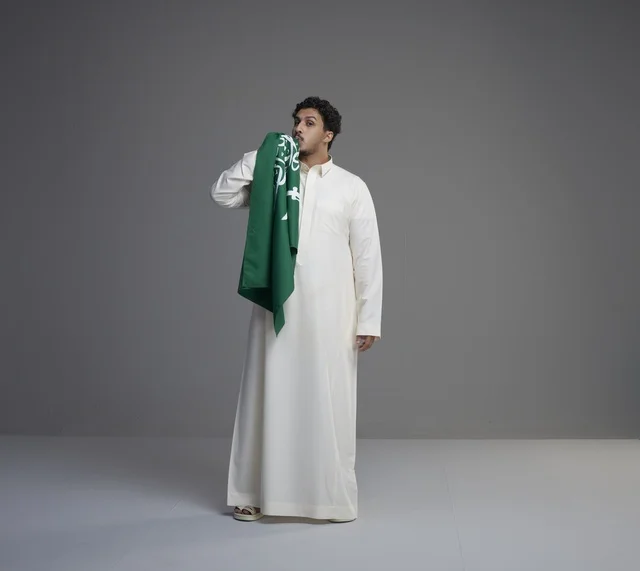 شاب سعودي يقبل العلم الوطني في استوديو