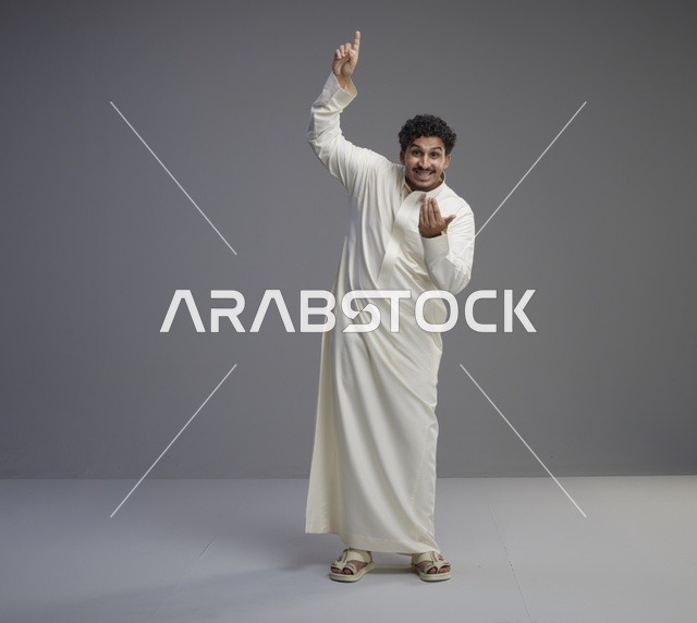 رجل سعودي بالثوب الأبيض يشير للأعلى في استوديو