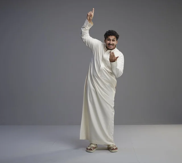 رجل سعودي بالثوب الأبيض يشير للأعلى في استوديو