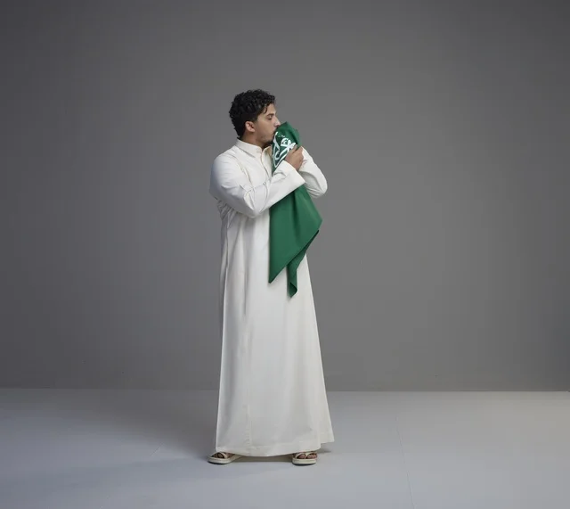 شاب سعودي يقبل العلم الوطني السعودي في الاستوديو