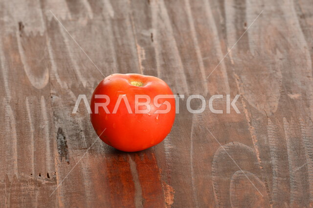 صورة مقربة لحبة الطماطم الحمراء على سطح خشبي