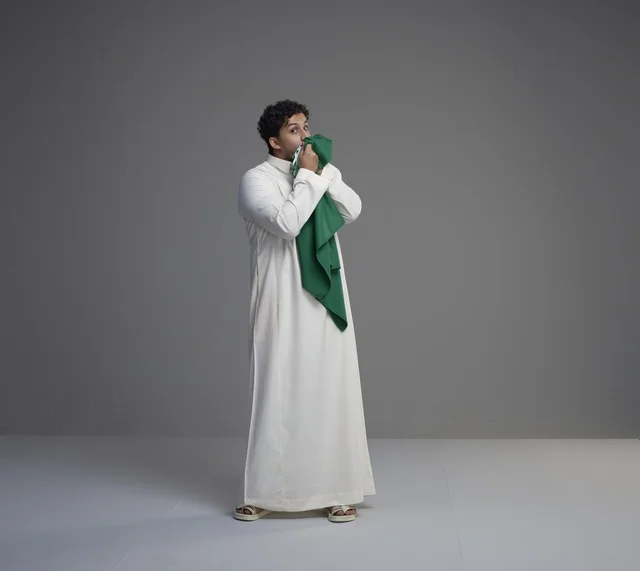 Saudi Man Kissing National Flag in Studio Setting