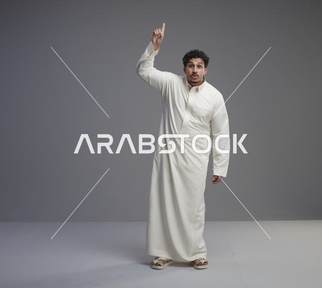 رجل سعودي بالثوب الأبيض يشير للأعلى في استوديو