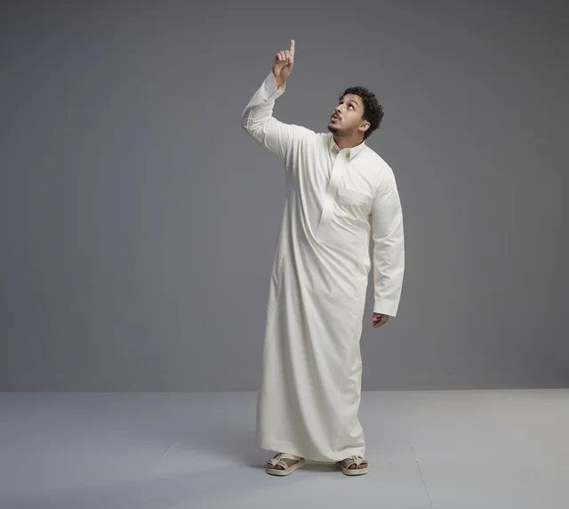 Saudi Man in White Thobe Pointing Up on Gray Background