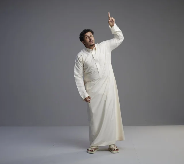 رجل سعودي بالثوب التقليدي يشير إلى الأعلى