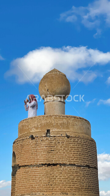 A Saudi Arabian Gulf man standing over an ancient mosque, praying to God, worshiping and getting closer to God, Islam and worship
