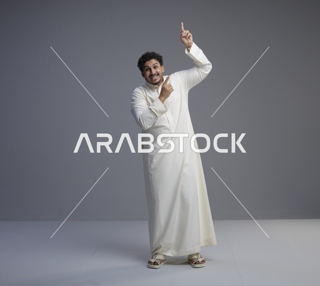 رجل سعودي بالثوب الأبيض يشير للأعلى في الاستوديو