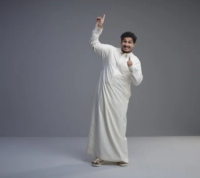 Saudi Man in Traditional White Thobe Pointing Up in Studio