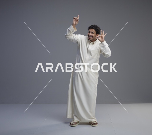 رجل سعودي بالثوب الأبيض يؤدي إشارة موافق في الاستوديو