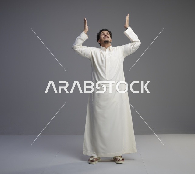 رجل سعودي بالثوب الأبيض التقليدي في وضعية الدعاء