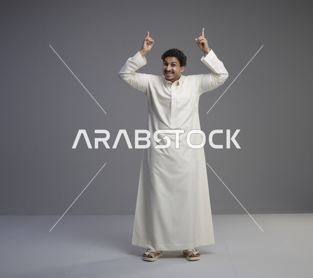 رجل سعودي بالثوب الأبيض يشير للأعلى في استوديو
