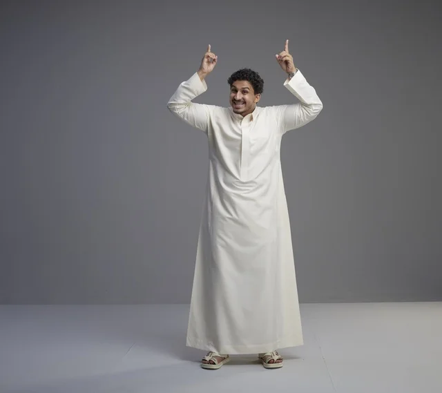 رجل سعودي بالثوب الأبيض يشير للأعلى في استوديو