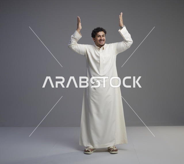رجل سعودي بالثوب الأبيض يرفع يديه للأعلى