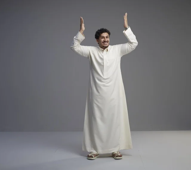 رجل سعودي بالثوب الأبيض يرفع يديه للأعلى