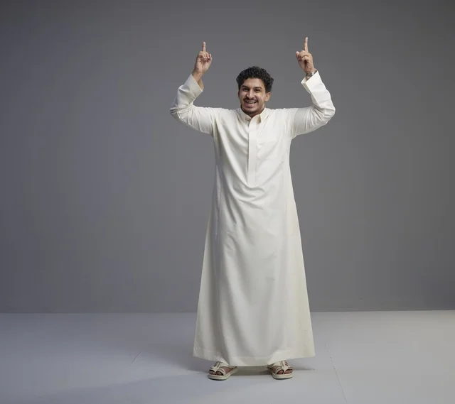 رجل سعودي بالثوب الأبيض يشير للأعلى بخلفية رمادية