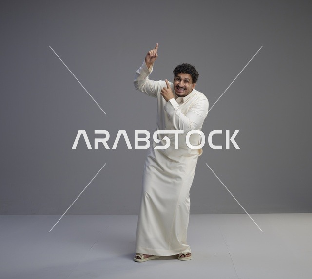 رجل سعودي بالثوب الأبيض يشير للأعلى في استوديو