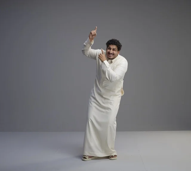 رجل سعودي بالثوب الأبيض يشير للأعلى في استوديو