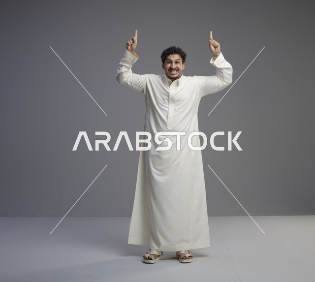 رجل سعودي بالثوب الأبيض يشير للأعلى في استوديو