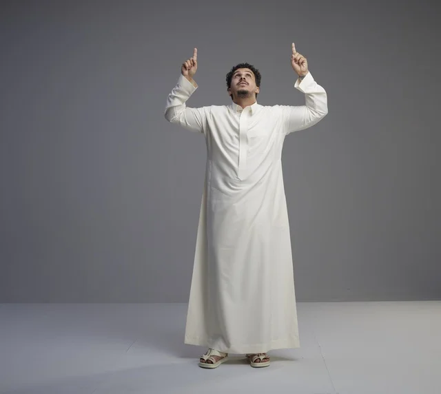 رجل سعودي بالثوب الأبيض يشير للأعلى في استوديو