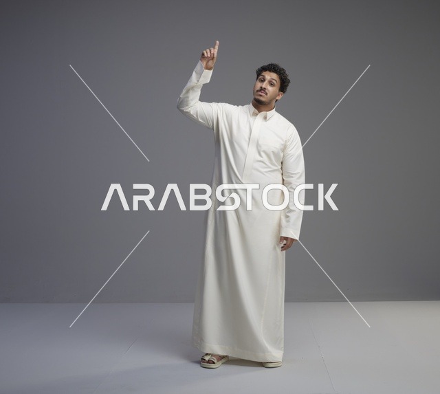 رجل سعودي بالثوب الأبيض يشير للأعلى في الاستوديو