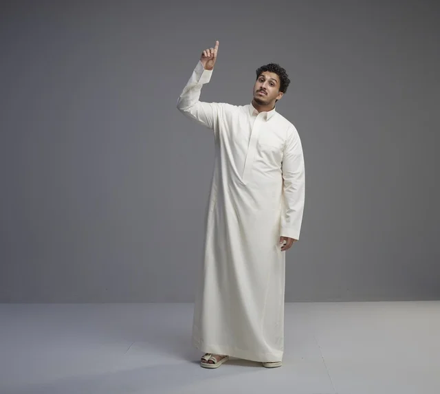 رجل سعودي بالثوب الأبيض يشير للأعلى في الاستوديو