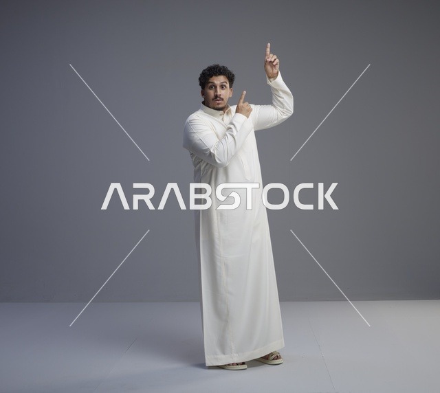 رجل سعودي بالثوب الأبيض يشير للأعلى بتعبير مندهش