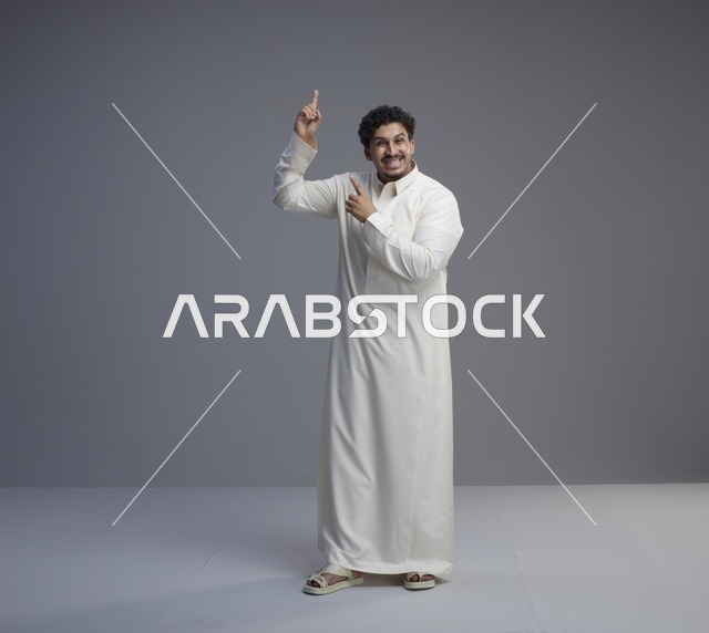رجل سعودي بالثوب الأبيض يشير للأعلى في استوديو