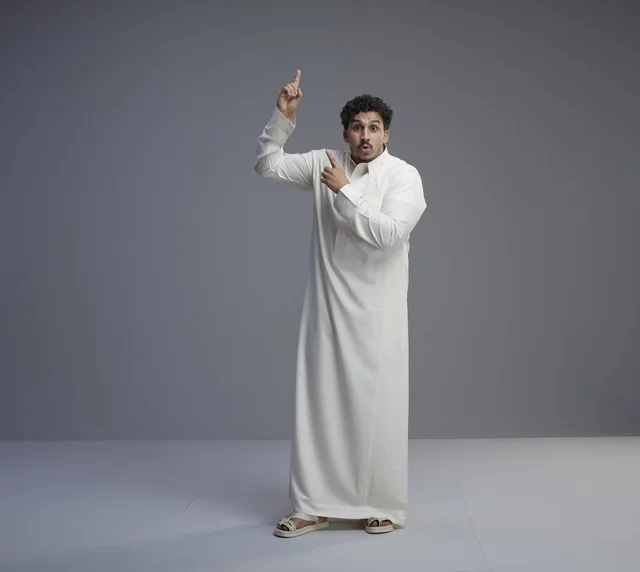 رجل سعودي بالثوب التقليدي يشير للأعلى بدهشة