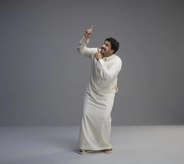 رجل سعودي بالثوب التقليدي يشير للأعلى