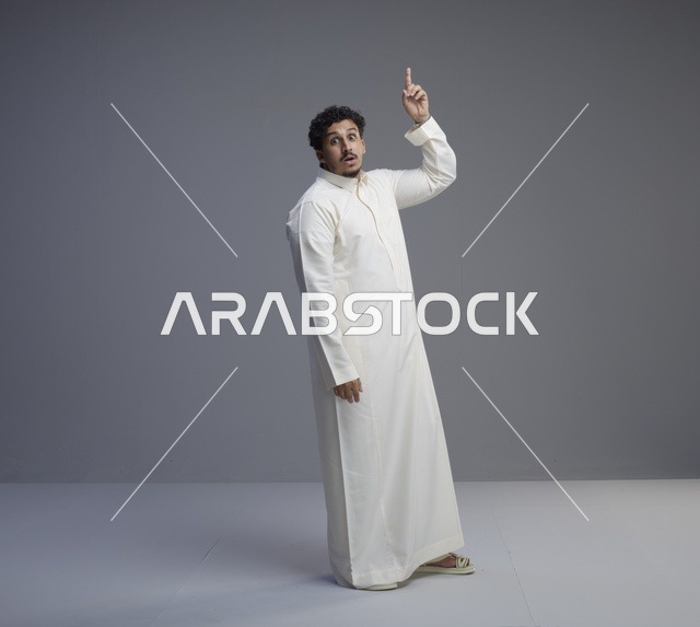 رجل سعودي بالثوب الأبيض يشير للأعلى بدهشة