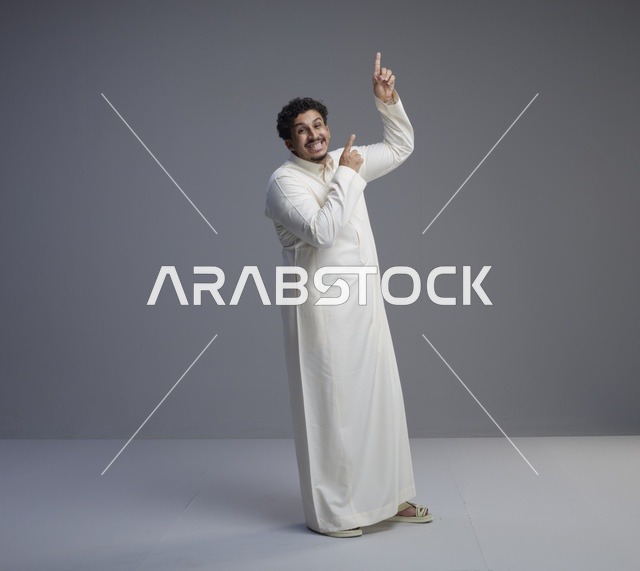 رجل سعودي بالثوب الأبيض يشير للأعلى في استوديو