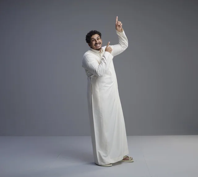 رجل سعودي بالثوب الأبيض يشير للأعلى في استوديو