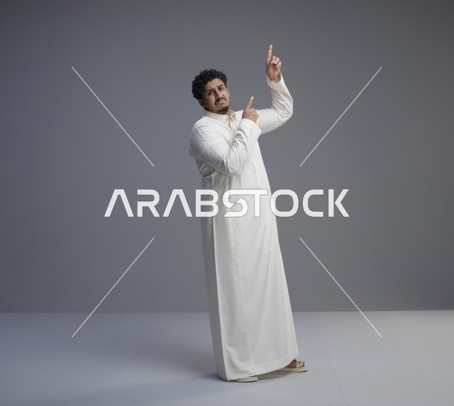 رجل سعودي بالثوب الأبيض يشير للأعلى في استوديو