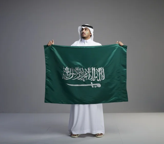 رجل سعودي يحمل العلم الوطني بفخر