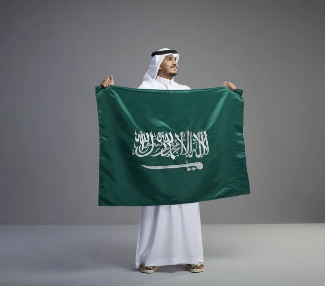 رجل سعودي يحمل العلم الوطني بفخر