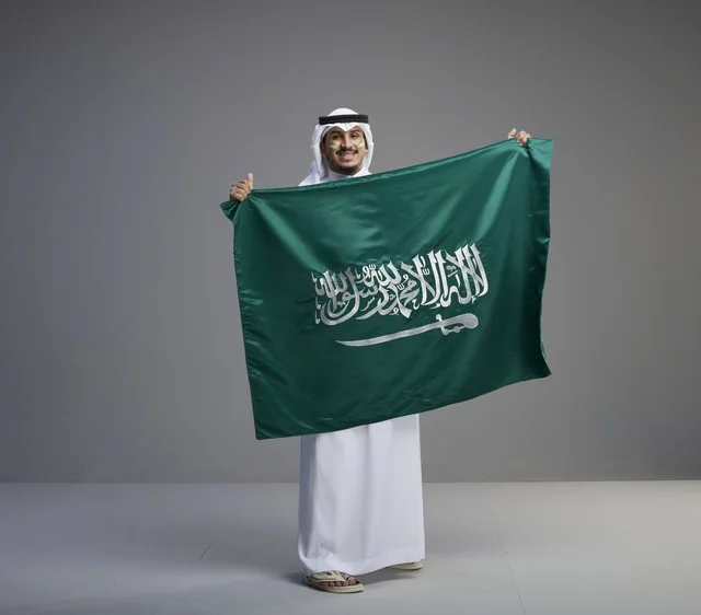 رجل سعودي يحمل العلم الوطني بفخر