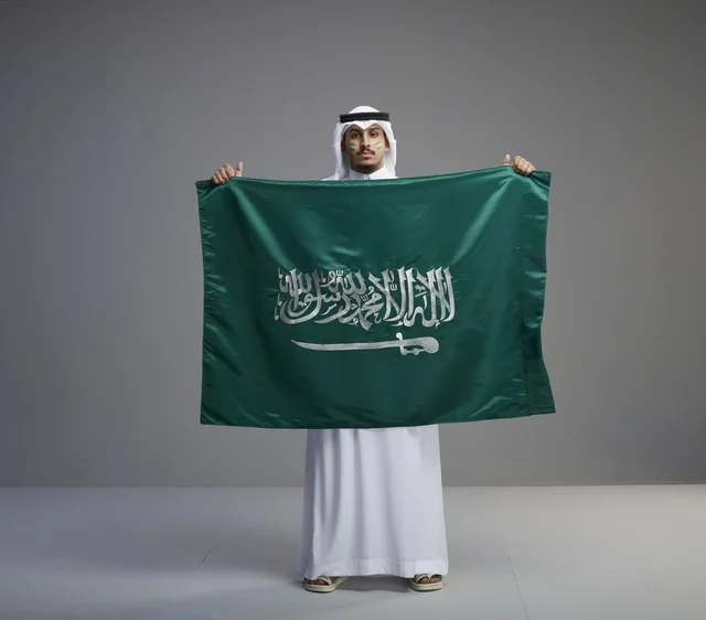 رجل سعودي يحمل العلم الوطني بفخر