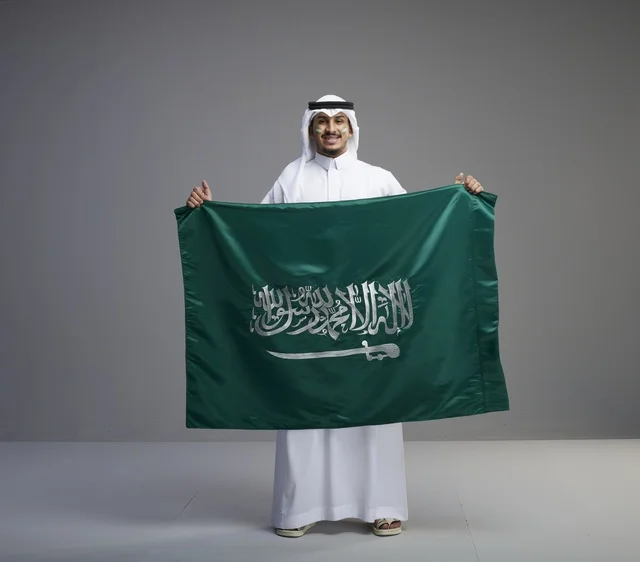 رجل سعودي يحمل العلم الوطني بفخر