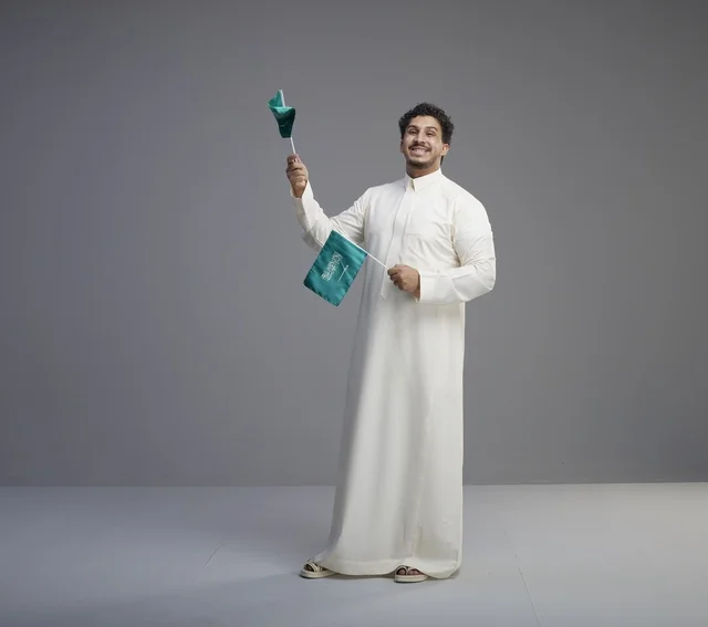Smiling Saudi Man Holding National Flag in Studio