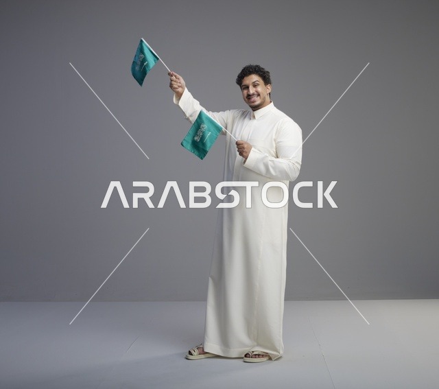 شاب سعودي مبتسم يلوح بعلم السعودية في الاستوديو