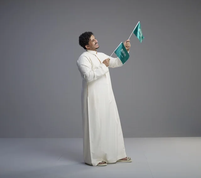 شاب سعودي يحمل علم السعودية في الاستوديو