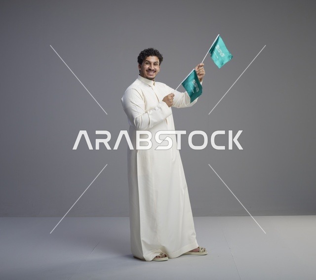 شاب سعودي مبتسم يلوح بعلم السعودية في الاستوديو