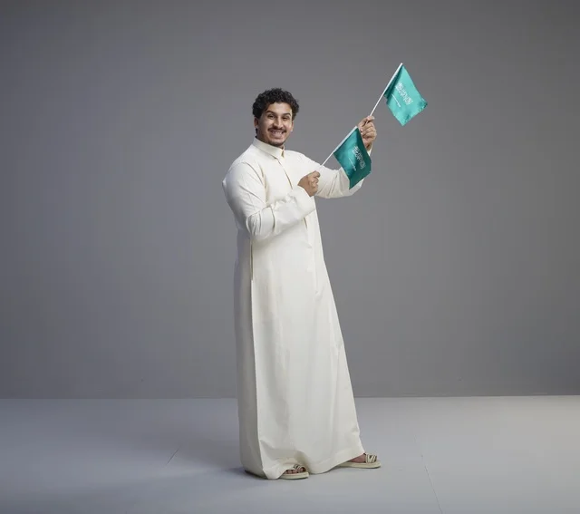 Smiling Saudi Man Waving Saudi Flag in Studio