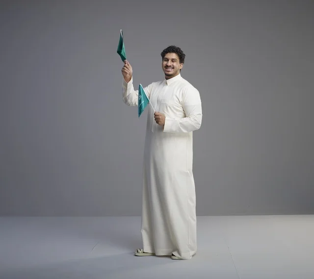 شاب سعودي بالثوب يلوح بعلم المملكة العربية السعودية
